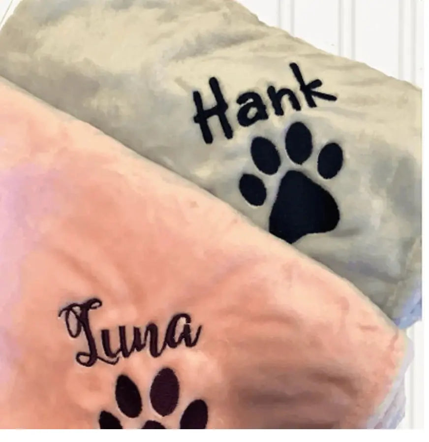 Personalised pet blanket with paw print and custom name embroidery in soft fabrics, featuring 'Hank' and 'Luna' designs.